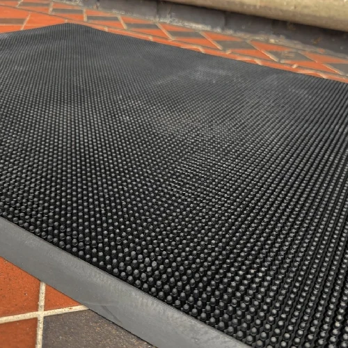 Angled view of textured rubber pins on a black mat