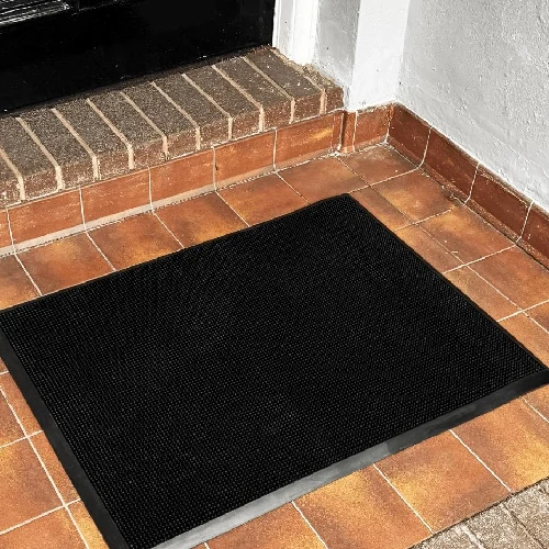 Black rubber fingertip doormat on a tiled entryway