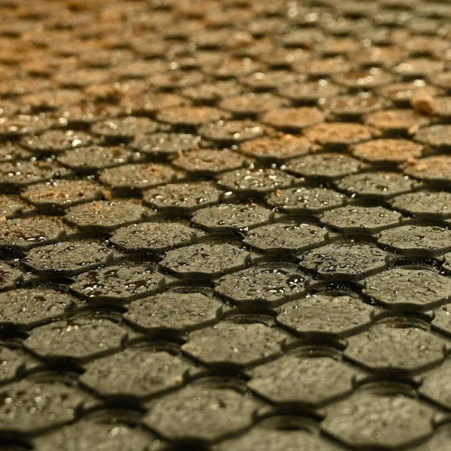 Close-up of wet black rubber matting with drainage holes
